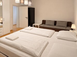 Una camera d'albergo con un letto, un divano, un comodino e una lampada.