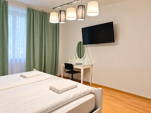 Una camera d'albergo con un letto, una scrivania con uno specchio e una TV a schermo piatto montata a parete.