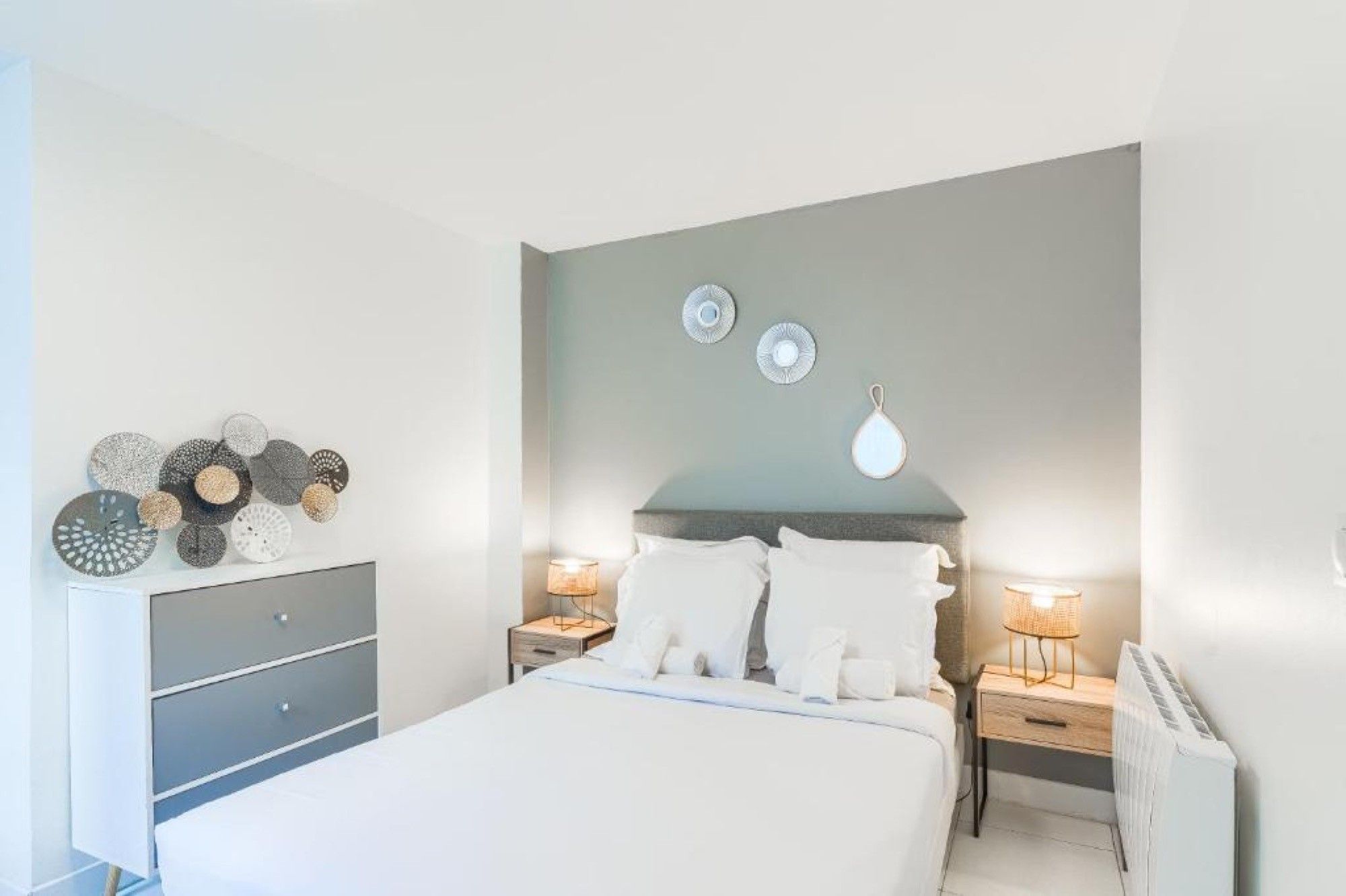 Une chambre à coucher comprenant un lit, des tables de chevet, une commode et des éléments de décoration murale.