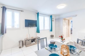 Un comedor moderno con una mesa dispuesta para dos, un televisor montado en la pared y vistas al exterior a través de amplios ventanales.