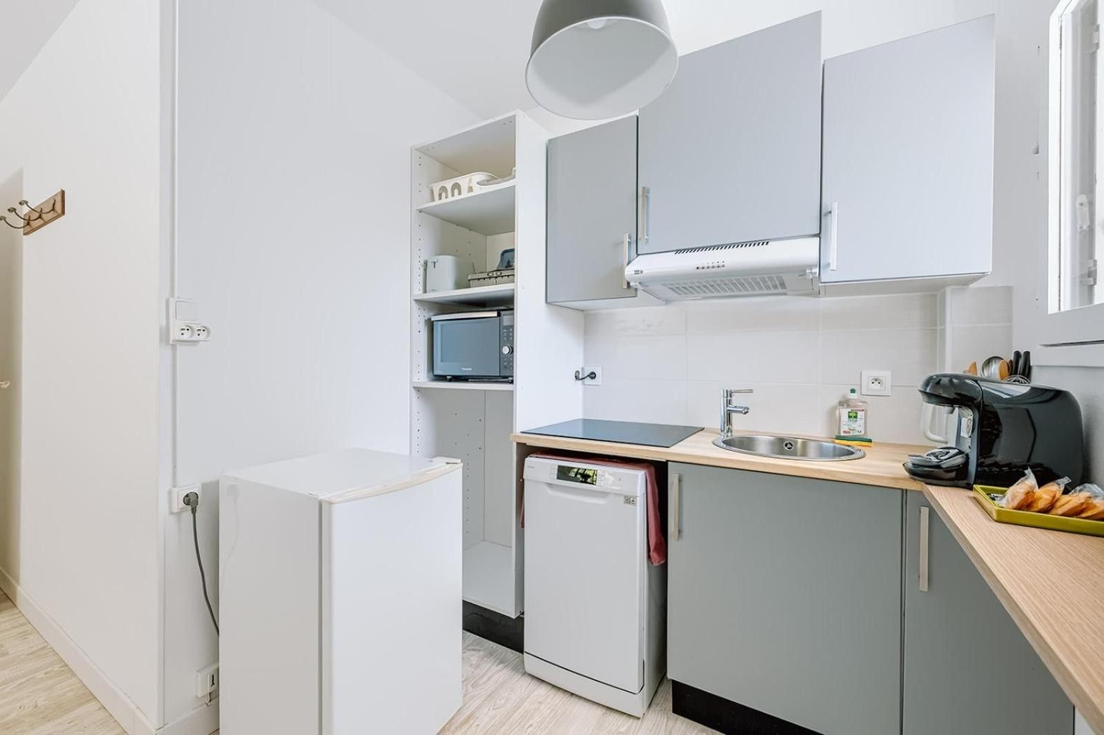 A compact kitchen with a built-in microwave, a coffee maker, and a dishwasher.