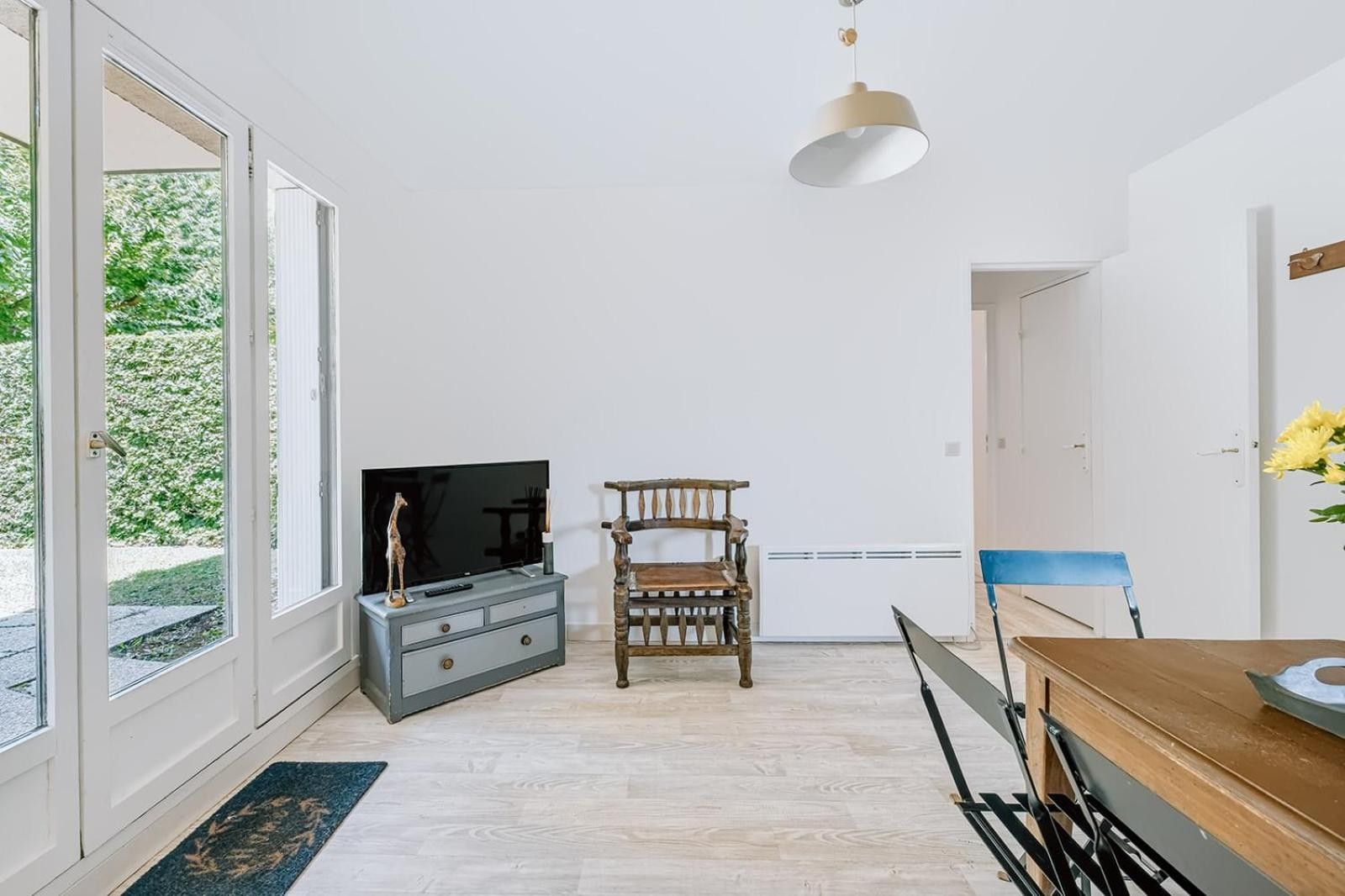Una sala de estar moderna con televisor, muebles de madera y un ventanal grande.