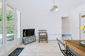 Una sala de estar moderna con televisor, muebles de madera y un ventanal grande.