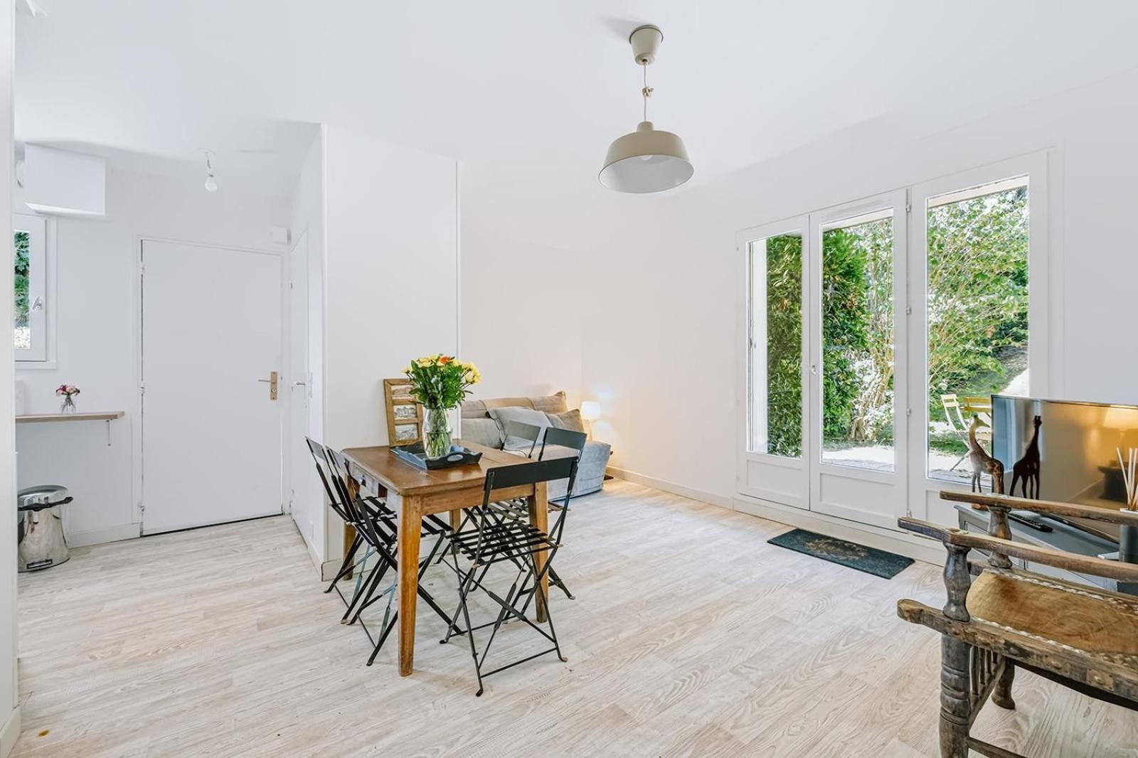 Een ruime kamer met een houten eettafel, stoelen, een bank en een televisie.