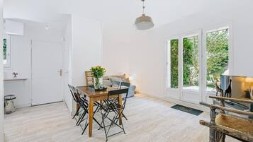 Een ruime kamer met een houten eettafel, stoelen, een bank en een televisie.