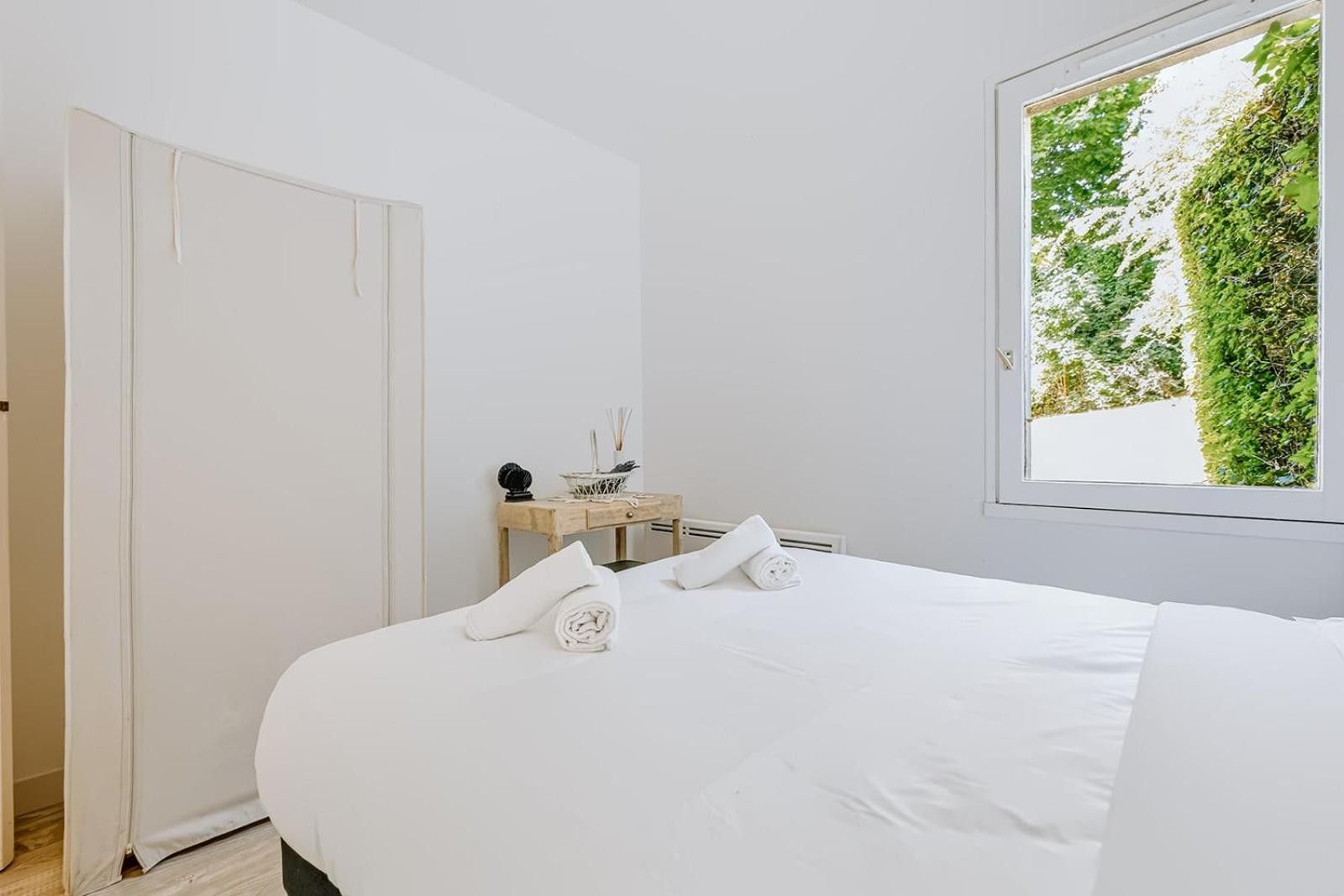 Una camera da letto con un letto grande, un comodino con una lampada e una finestra vista verde.