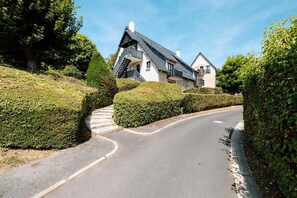 A residential street with a curved road, a staircase leading to a house, and well-maintained hedges. - Apartment 'Le Jardin Canisy - Piscine - Tennis' with Shared Pool, Private Terrace and Wi-Fi (Saint-Arnoult)