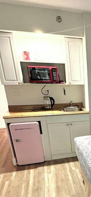 A compact kitchenette with a microwave, a small refrigerator, and a sink. - Oceanview Deluxe Studio w/pool & kitchenette (Daytona Beach)