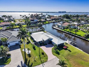 A residential area with a canal, houses, and palm trees. - Gulf Access Water View Home, No Bridges, 1 Block access to Caloosahatchee River (Cape Coral)
