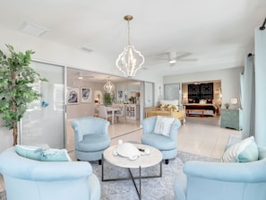 A spacious living room with light blue armchairs, a coffee table, and a modern chandelier. - Gulf Access Water View Home, No Bridges, 1 Block access to Caloosahatchee River (Cape Coral)