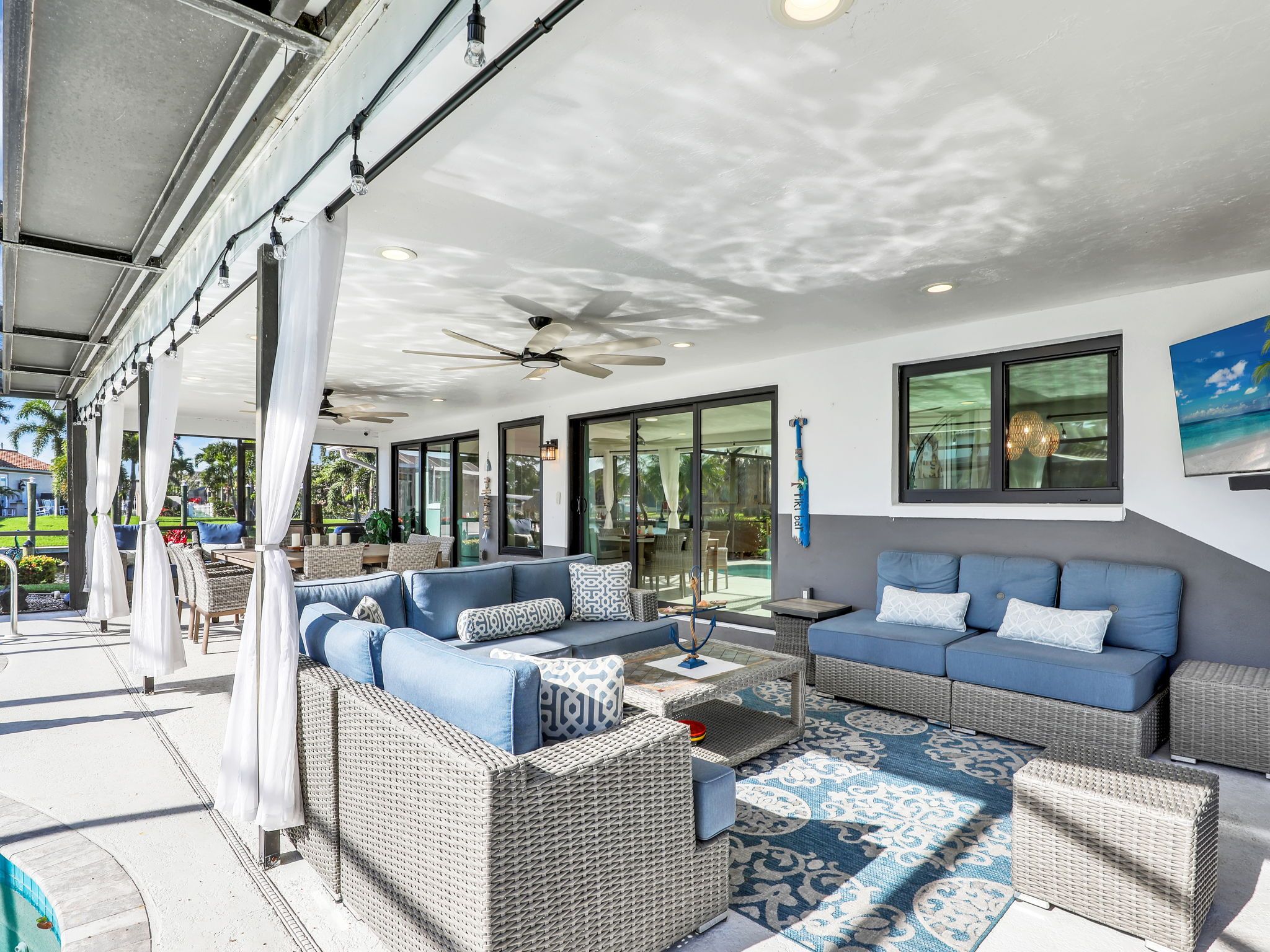 A covered outdoor seating area with wicker furniture and a patterned rug.
