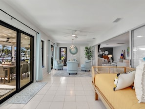 A spacious living area with a large bed, two armchairs, a dining table, and a view of the outdoors. - Gulf Access Water View Home, No Bridges, 1 Block access to Caloosahatchee River (Cape Coral)