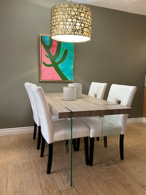 A dining table with six white chairs, a wooden top, and a clear glass base. - Updated Old Town 1st Fl Parking Pool Spa Hot Tub (Scottsdale)