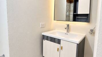 A bathroom with a white sink, wooden cabinets, a mirror, and a towel rack.