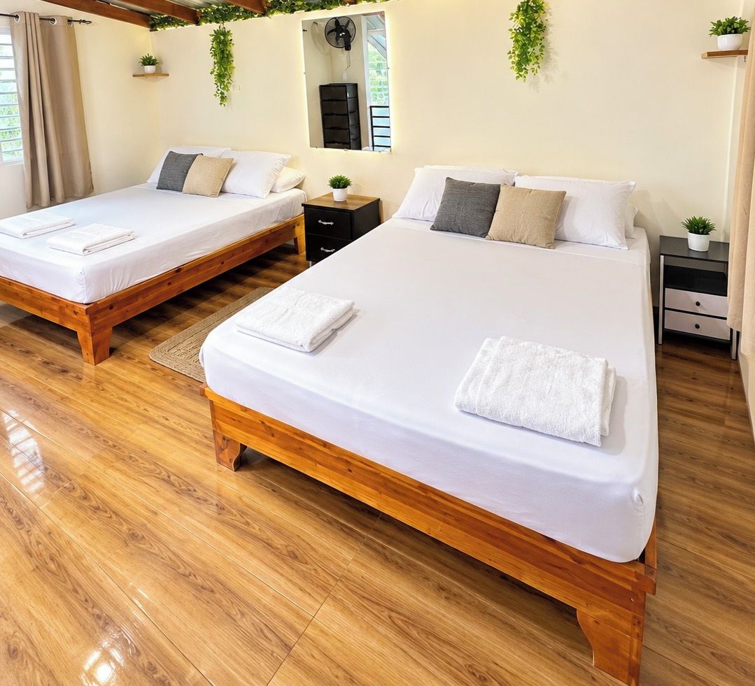 Une chambre d’hôtel avec deux lits, un plancher en bois et un miroir au mur.