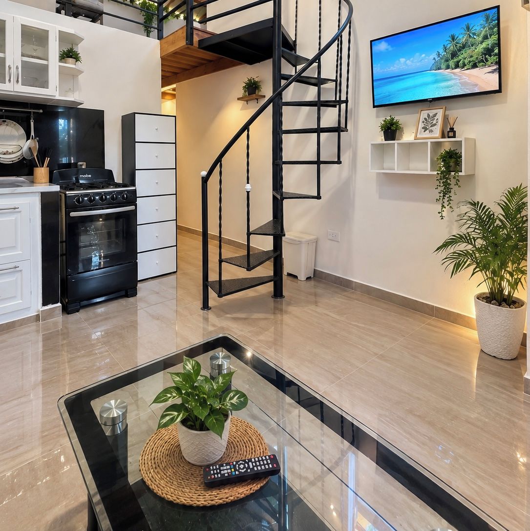 A modern kitchen with a black stove, white cabinets, and a black spiral staircase.