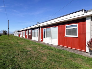 A row of single-story mobile homes with red and white exteriors, large windows, and a grassy front yard. - 122 Norton Park (Dartmouth)