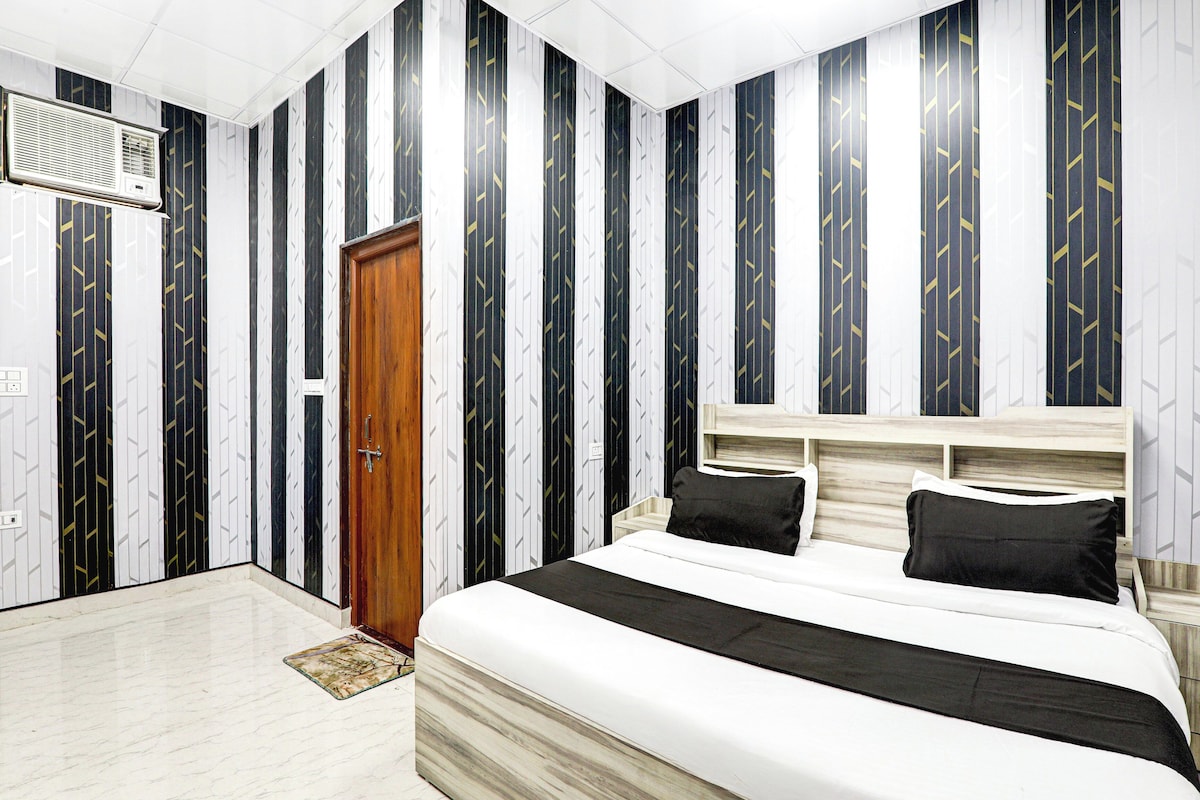 A bedroom with a bed, a wooden door, and a wall with vertical stripes.