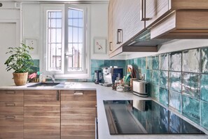 A modern kitchen with wooden cabinets, a stainless steel sink, and a large window. - Elegant Parisian Apartment minutes from Trocadero – Passy, 16th Arrondissement (Paris)