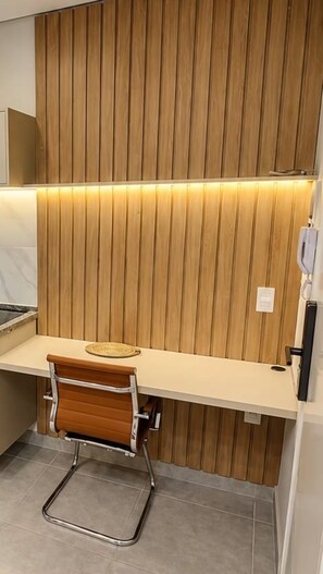 A modern kitchen with a wooden panel wall, a stainless steel sink, and a brown chair. - Residencial Madalena (Indaiatuba)