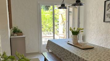 Un coin repas avec une table dressée pour deux personnes, un banc et une vue sur l’extérieur.