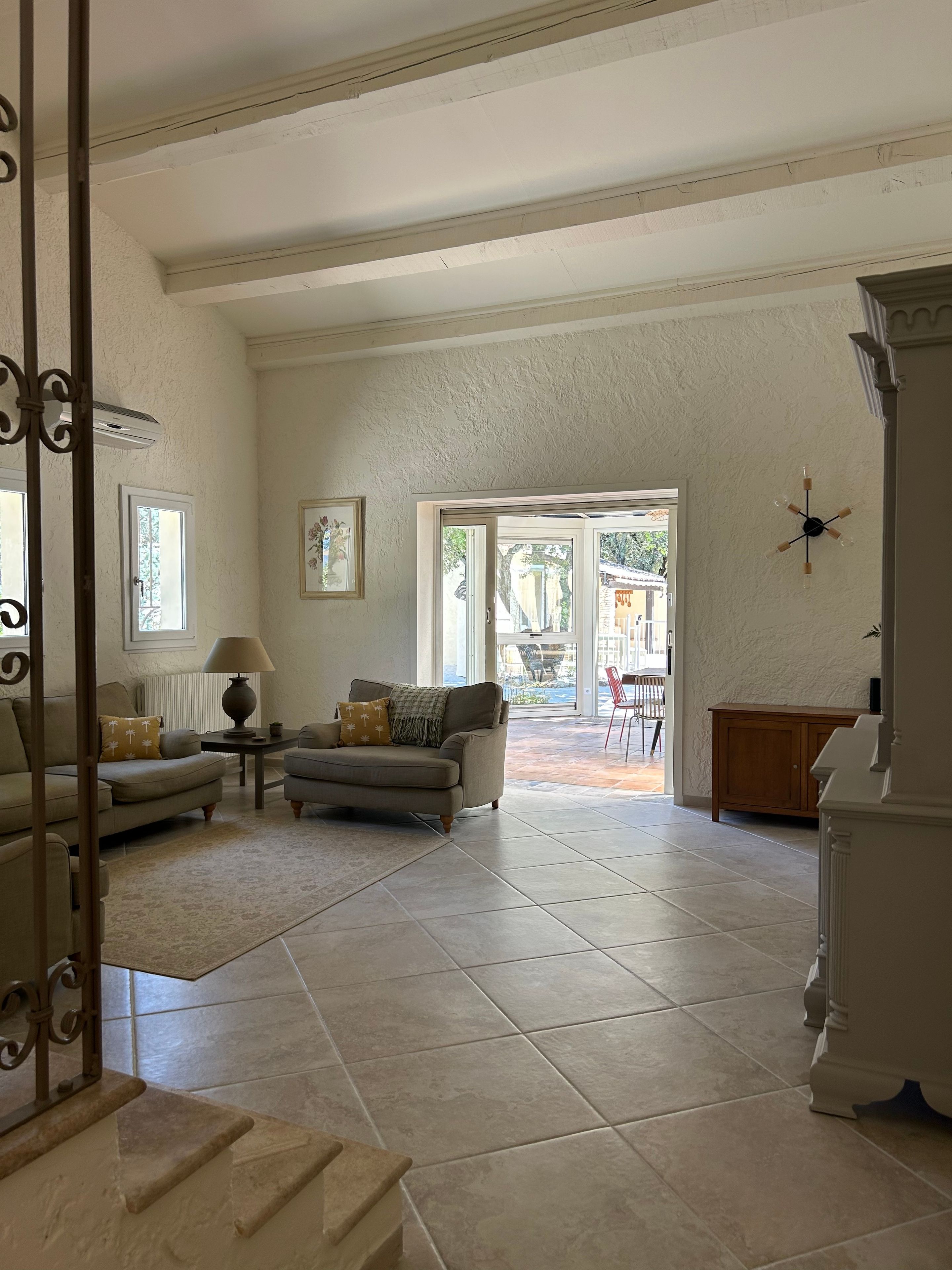 A spacious living area with a sofa, a coffee table, and a lamp. There is a door leading to an outdoor patio area.