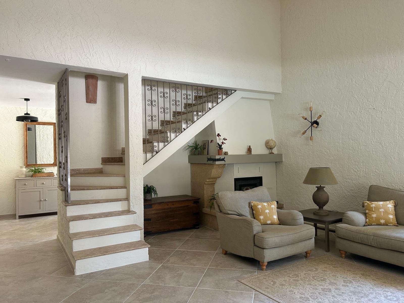 Un salon avec un escalier, une cheminée et un canapé.