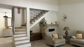 Un salon avec un escalier, une cheminée et un canapé.