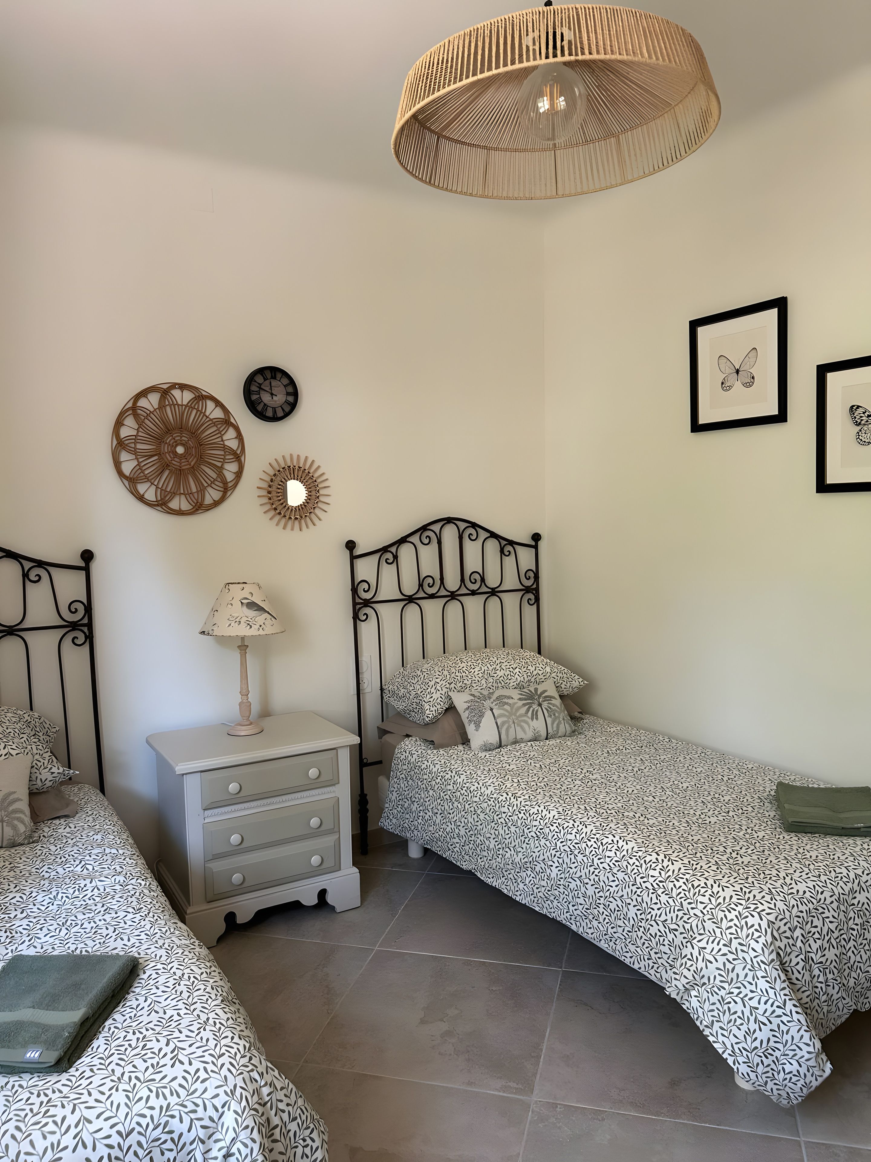 A bedroom with a bed, bedside table, lamp, wall decor, and a hanging light fixture.