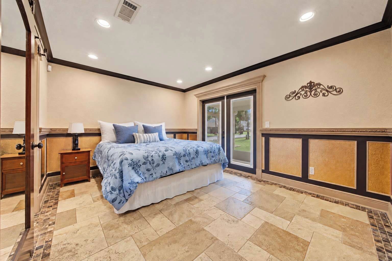 A bedroom with a bed, nightstands, a window, and a decorative wall piece.