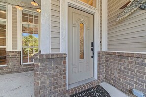 A house entrance with a grey door, brick columns, and a metal doormat. - The Coastal Nest - a duplex perfect for family groups that sleeps 12 (6 per unit) (Pensacola)