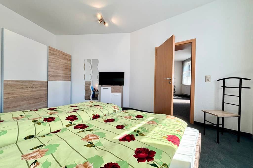 Habitació d'hotel amb llit, escriptori, cadira i televisió.
