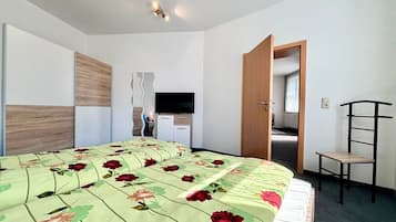 Habitació d'hotel amb llit, escriptori, cadira i televisió.
