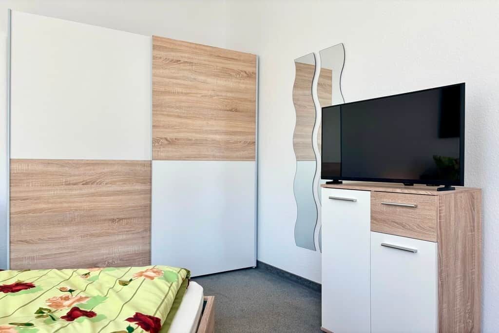 Ein Schlafzimmer mit einem Bett, einem Fernseher auf einem Schrank und einem Spiegel.