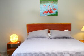 A bedroom with a bed, two bedside lamps, a nightstand, and a painting of flamingos on the wall. - Beautiful 5-bedroom Colonial house with pool in Historic Centro Mérida (Mérida)