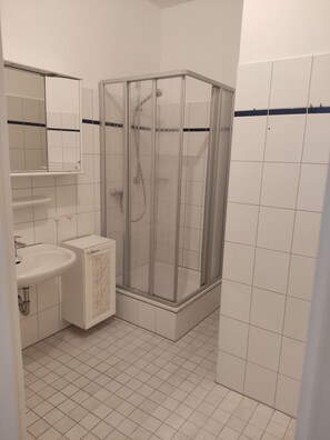 Une salle de bain avec une douche, un lavabo et un miroir.