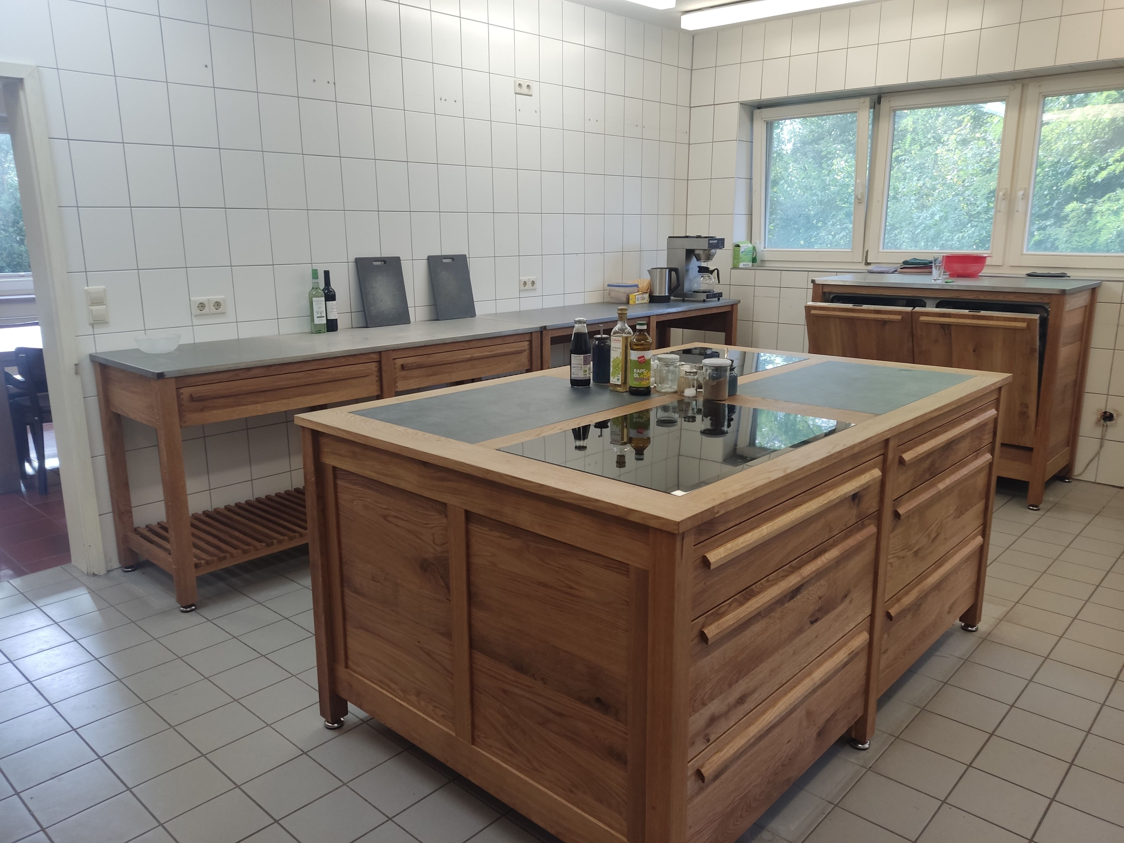 Una cocina con una isla central, armarios de madera y un ventanal con vistas a la vegetación.