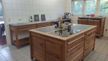 Una cocina con una isla central, armarios de madera y un ventanal con vistas a la vegetación.