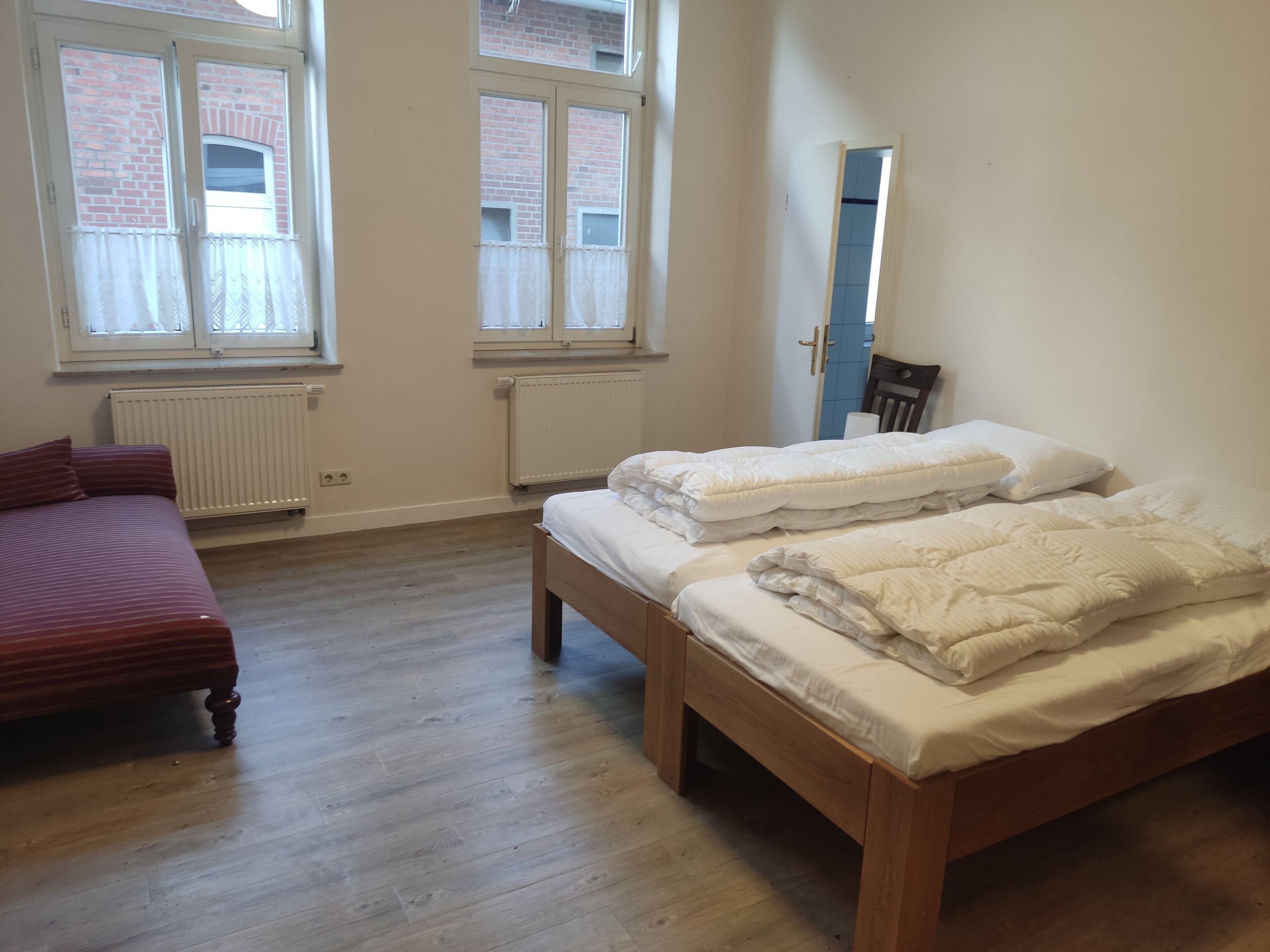 Une chambre avec deux lits, un canapé et une fenêtre.