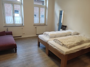 Une chambre avec deux lits, un canapé et une fenêtre.