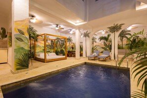 A room with a large bed, a pool, and lounge chairs. - Beautiful 13 BR House in the Old City (Cartagena de Indias)