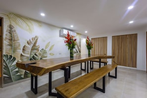 A dining area with a long wooden table, benches, and two vases with flowers. - Beautiful 13 BR House in the Old City (Cartagena de Indias)