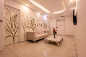 A modern living room with a beige sofa, a coffee table, and a wall-mounted TV. - Beautiful 13 BR House in the Old City (Cartagena de Indias)