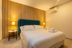A hotel room with a bed, two bedside lamps, a wooden slat wall, and an air conditioning unit. - Beautiful 13 BR House in the Old City (Cartagena de Indias)