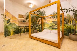 A room with a wooden four-poster bed, a dining area with chairs, and a wall mural with tropical plants. - Beautiful 13 BR House in the Old City (Cartagena de Indias)