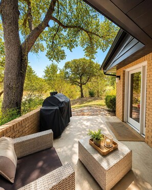 An outdoor patio with wicker furniture, a barbecue grill, and a view of trees and a stone pathway. - Fully Furnished 3BR + Bonus Room, Golf Course, Horseshoe Bay (Horseshoe Bay)