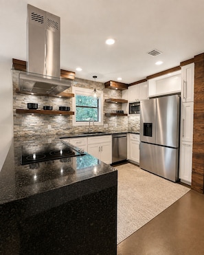 A modern kitchen with a granite countertop, stainless steel appliances, and a stone backsplash. - Fully Furnished 3BR + Bonus Room, Golf Course, Horseshoe Bay (Horseshoe Bay)