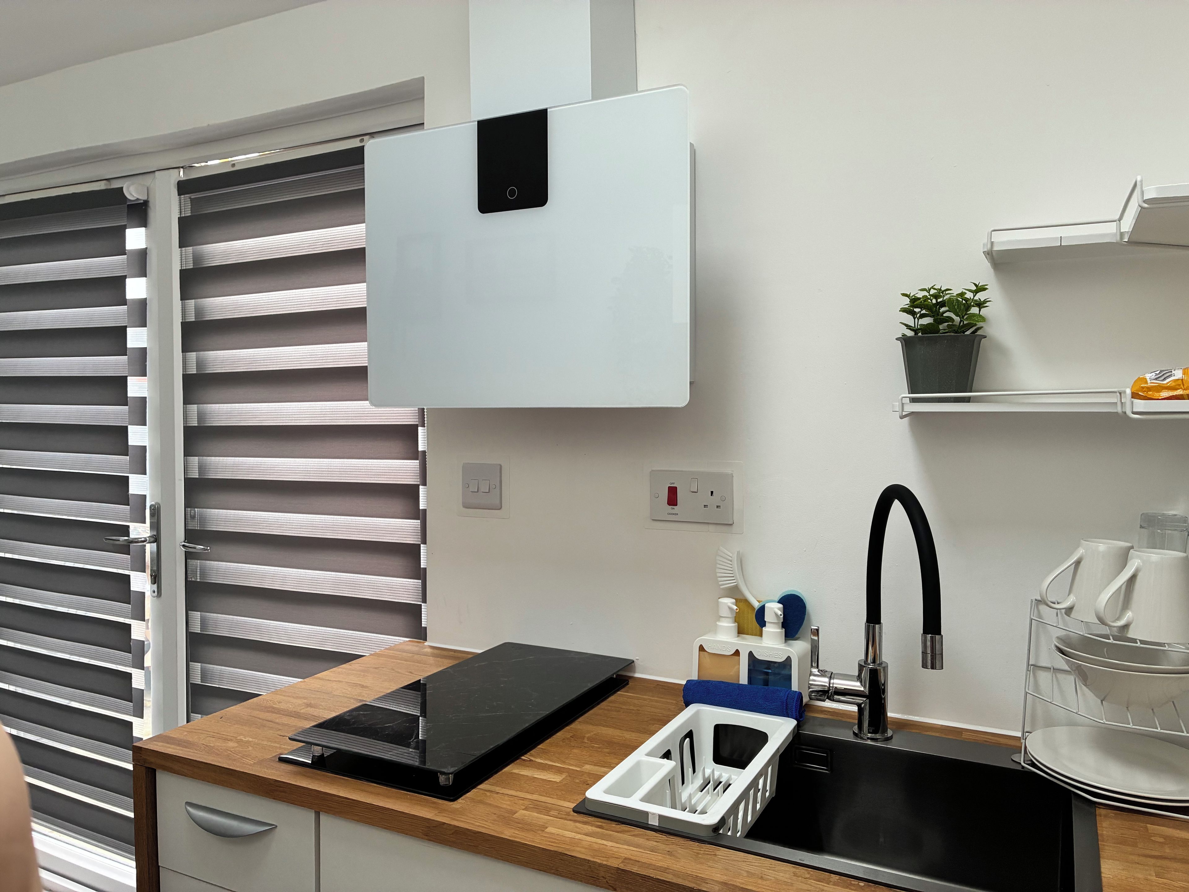 Una cocina moderna con lavavajillas integrado, un lavaplatos con grifo y una ventana con persianas.