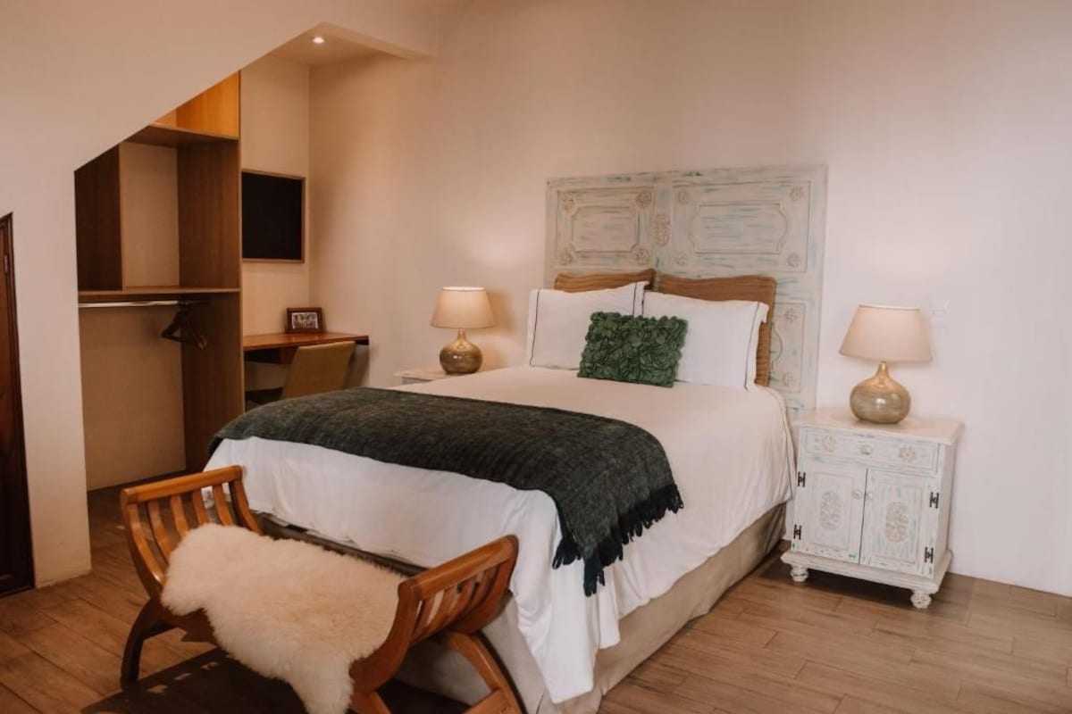 A bedroom with a bed, bedside tables, a chair, a wardrobe, and a television.
