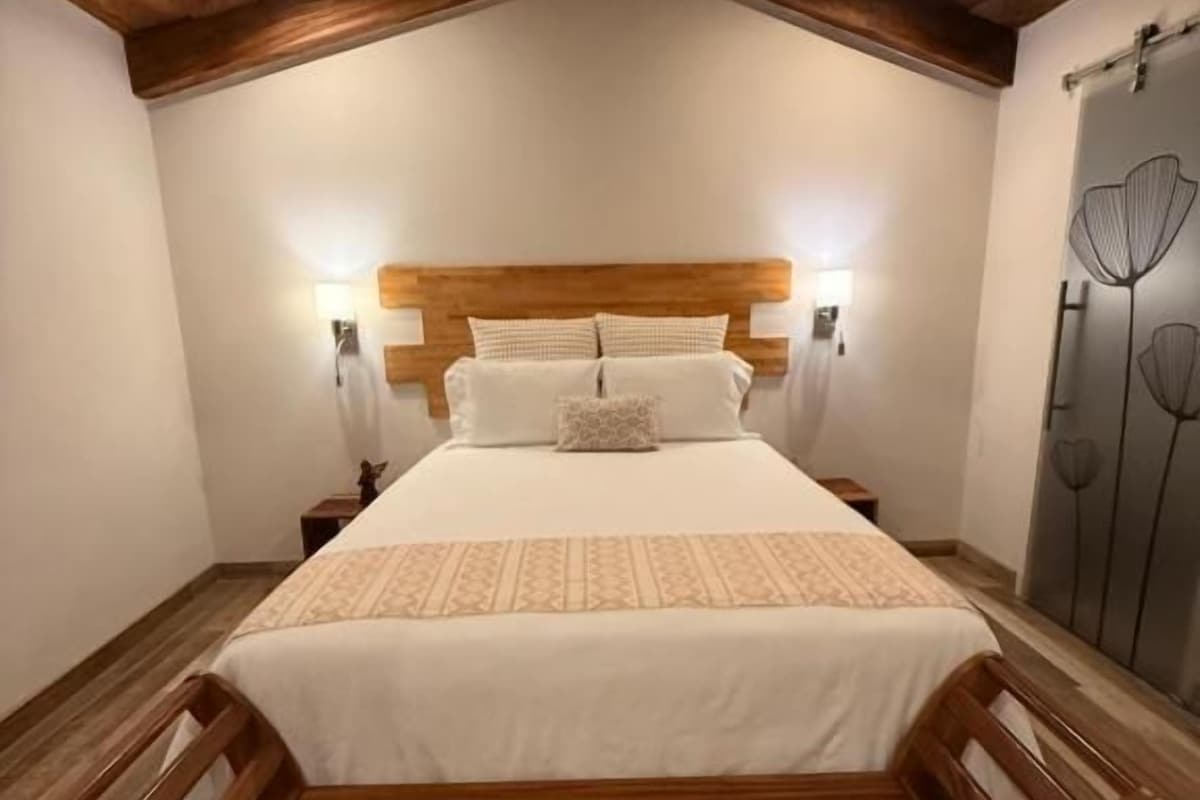 A bedroom with a wooden bed, nightstands, and a bench.